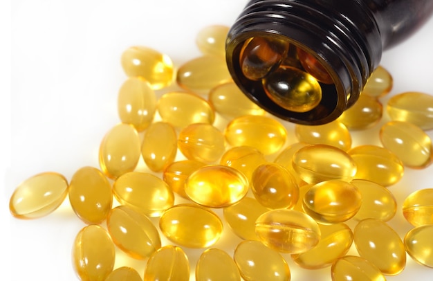 Omega-3 fish fat oil capsules spill out from bottle