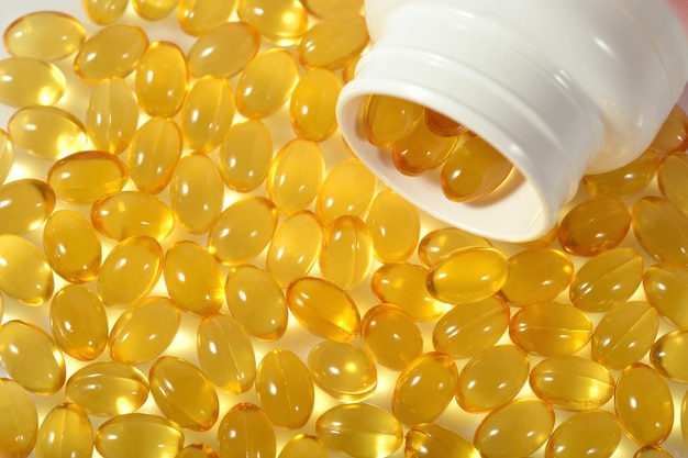 Photo omega-3 fish fat oil capsules spill out from bottle