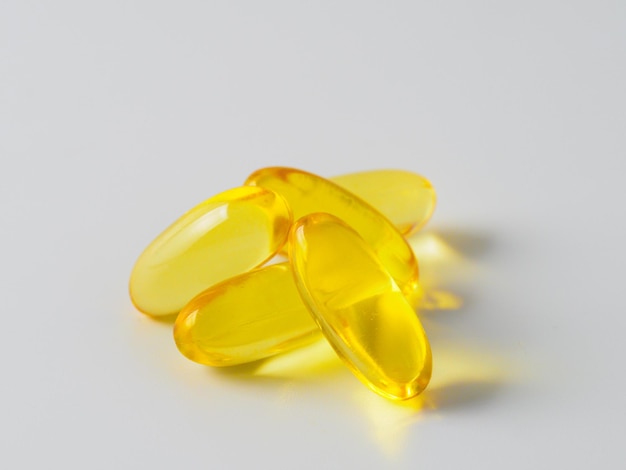 Capsule di olio di pesce omega 3 isolate su priorità bassa bianca. capsule di colore dorato: vitamina e, d o multivitaminico.