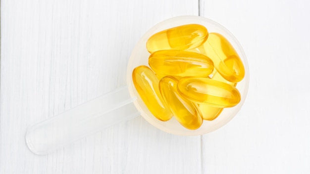 Omega-3 gele capsules in een plastic lepel, voedingssupplementen, close-up, bovenaanzicht.