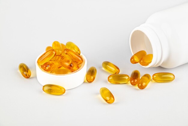 Omega 3 vistraancapsules die uit fles op witte achtergrond morsen