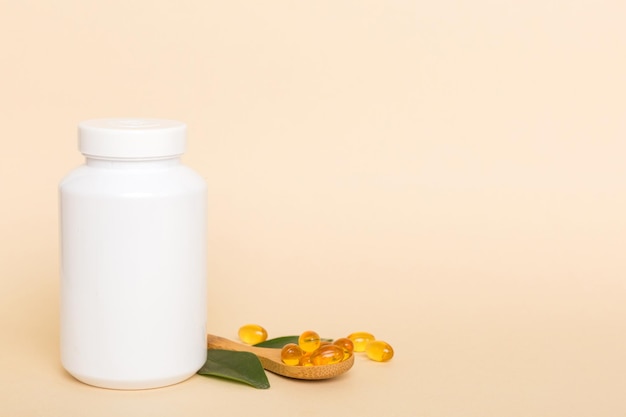 Omega3-capsules liggen in witte fles op een tafel met groene bladerenachtergrond Visolietabletten Biologisch actieve additieven omega 6 omega 9 vitamine AED vitamine D3 bovenaanzicht met kopieerruimte