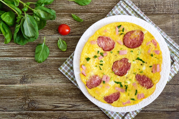 Omelet met ham, salami, kaas en Groenen op een plaat op een houten achtergrond. Ontbijt. Bovenaanzicht.