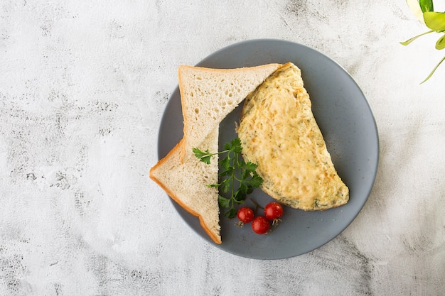 Omelet met kaas, cherry tomaten en zuurdesem toast geïsoleerd op witte marmeren achtergrond. Zelfgemaakt eten. Lekker ontbijt. Selectieve aandacht. Hotizontal foto.