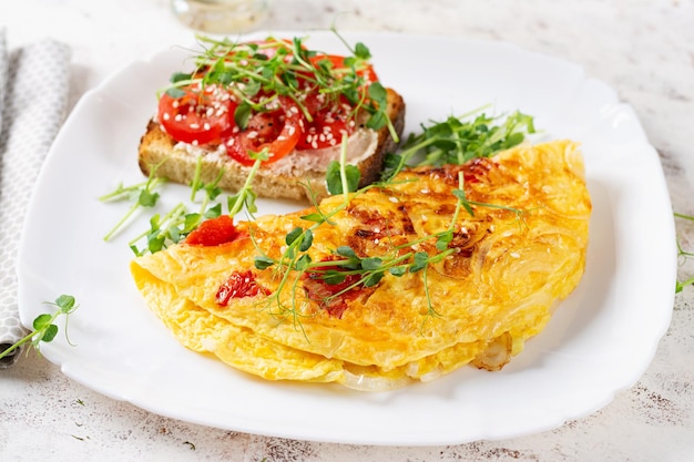 Foto omelet met kaas en toast met tomaten op een wit bord frittata italiaanse omelet