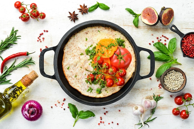 Omelet met tomaten en peterselie in een pan Voedsel voor het ontbijt Vrije ruimte voor uw tekst Bovenaanzicht