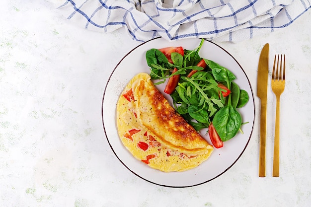 Omelet met tomaten en salade op witte plaat Frittata Italiaanse omelet Bovenaanzicht