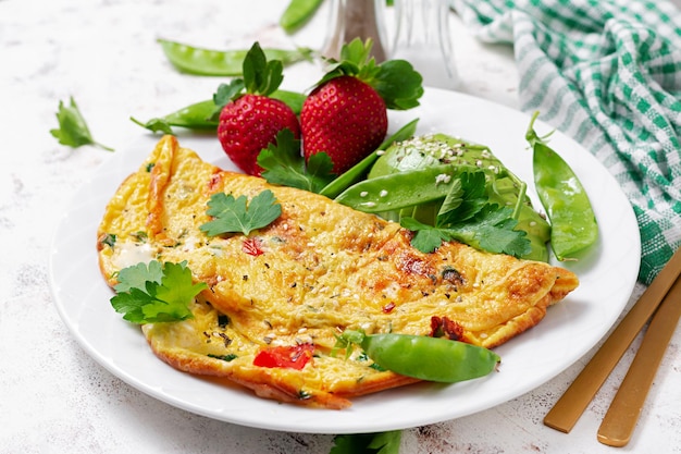 Omelet met tomaten fetakaas en avocado op wit bord