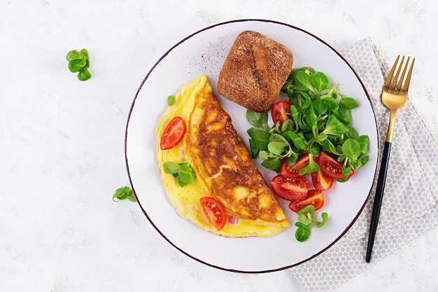 Omelet met tomaten, ham, kaas en veldsla op plaat. Frittata - Italiaanse omelet. Bovenaanzicht, overhead