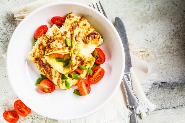 Omelet met zalm, kaas en groene uien op witte plaat, bovenaanzicht