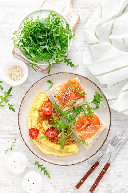 Omelet of omelet verse rucola en tomatensalade en toast met boter en gezouten zalm Ontbijt Bovenaanzicht