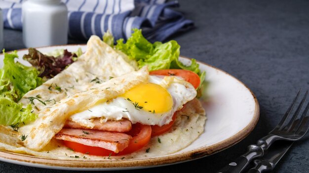 Omelet with fried egg bacon and tomatoes on a plate