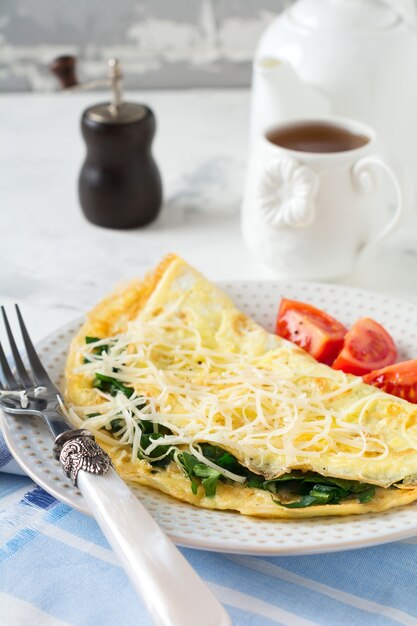 明るい表面での朝食にほうれん草、パセリ、チーズのオムレツ