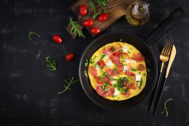 Frittata con prosciutto di pomodori e formaggio feta in padella vista dall'alto