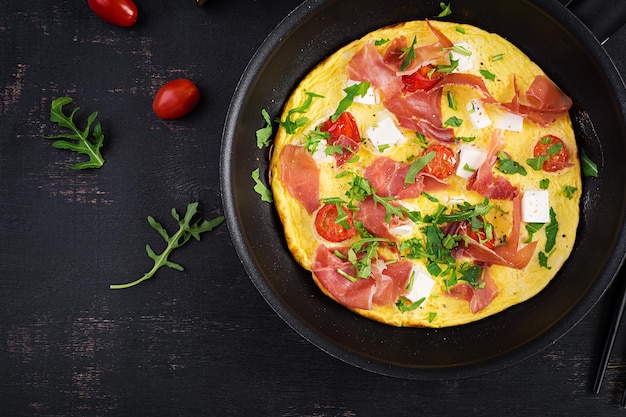 Foto frittata con prosciutto di pomodori e formaggio feta in padella vista dall'alto