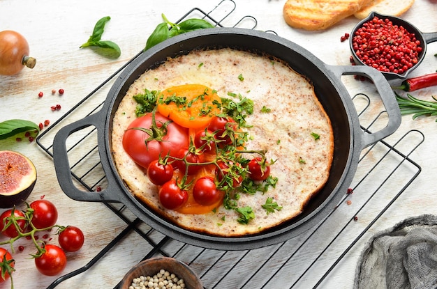 Omelet with tomatoes and parsley in a pan. food for breakfast.
free space for your text. top view.