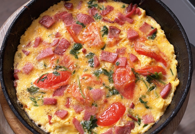 Omelet with tomatoes and sausage in pan. Rustic breakfast