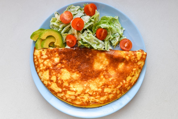 Omelet with vegetables on a plate. blue plate. view from above. Omelet with vegetables on a plate served for breakfast. View from above