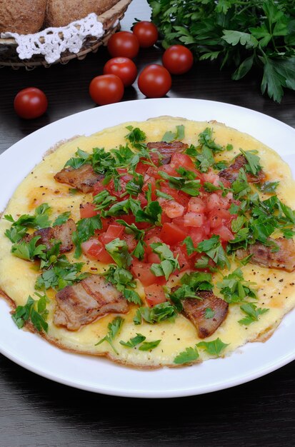 Omelette slices of fried bacon, tomatoes with herbs