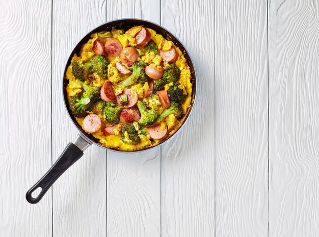 Omelette with broccoli and sausages in a skillet