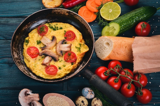 Omelette with mushrooms and fresh vegetables and nuts on a frying pan On a wooden background Top view Copy space