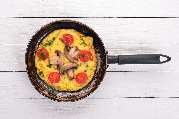 Omelette with mushrooms and fresh vegetables and nuts on a frying pan On a wooden background Top view Copy space