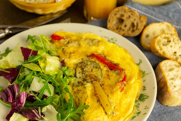 Omelette with vegetables and lettuce, bread and orange juice, breakfast