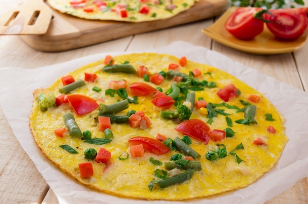 Photo omelette with vegetables on a wooden background. breakfast