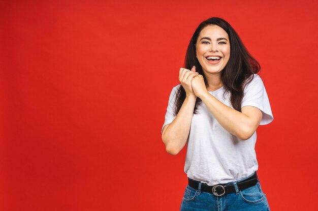 OMG Portrait of amazed shocked surprised young woman isolated over red background