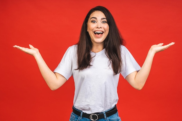 OMG Portrait of amazed shocked surprised young woman isolated over red background