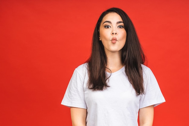 OMG Portrait of amazed shocked surprised young woman isolated over red background