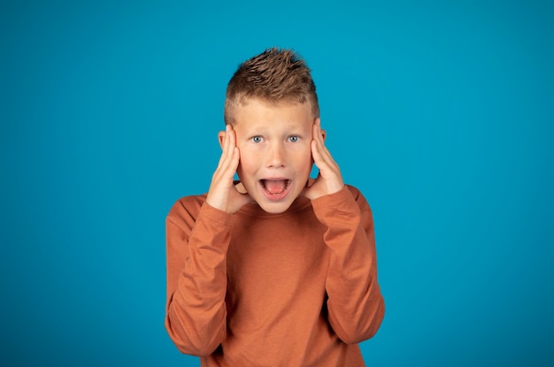 Omg portrait of shocked preteen boy touching face and looking at camera