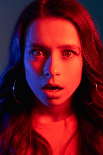 Omg reactie Cyberpunk portret Schokkend nieuws Fobieprobleem Overweldigd verbaasde vrouw met open mond in heldere kleurrijke gloeiende neon lichtblauwe rode kleur in de donkere nacht