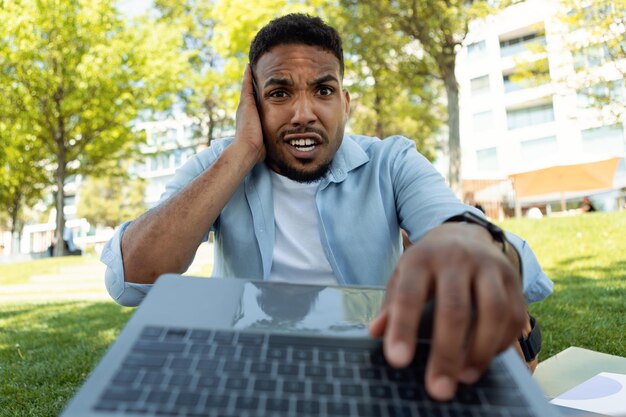 Omg shocked black man looking at laptop screen and grabbing\
head reading bad negative news web