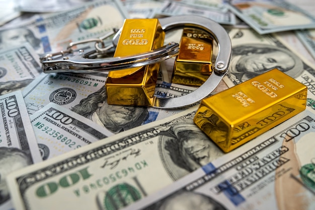 Omkopen concept goudstaven en handboeien in dollarbiljetten