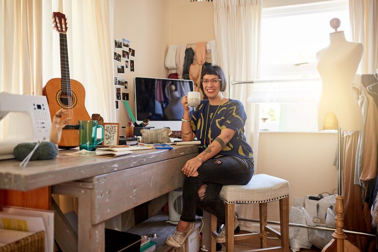 Foto omringd door haar creatieve inspanningen portret van een stijlvolle jonge ontwerper zittend in haar eclectische studio