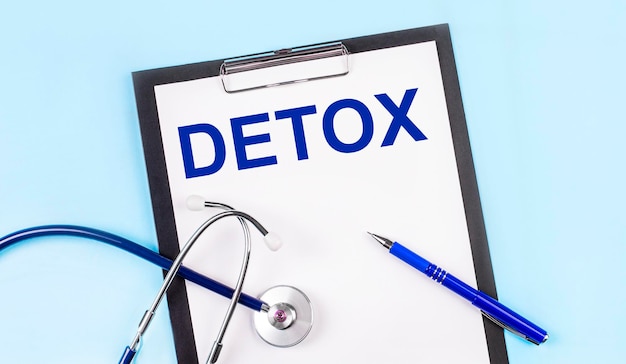 На синем фоне стетоскоп, ручка и планшет с бумагой и текстом detox medical concept