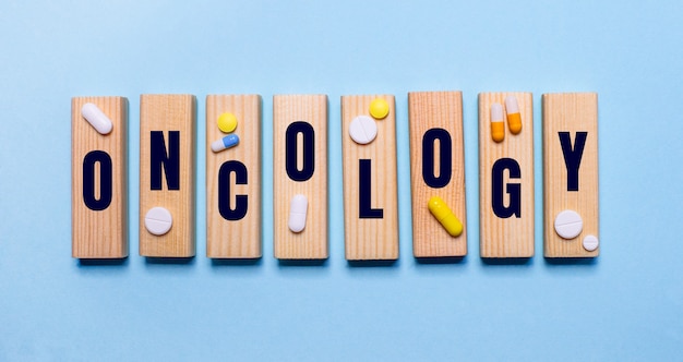 写真 青い背景に、oncologyという言葉と丸薬が付いた木製のブロック。医療の概念