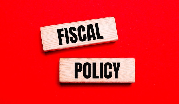 На ярко-красном фоне два светлых деревянных блока с надписью fiscal policy.