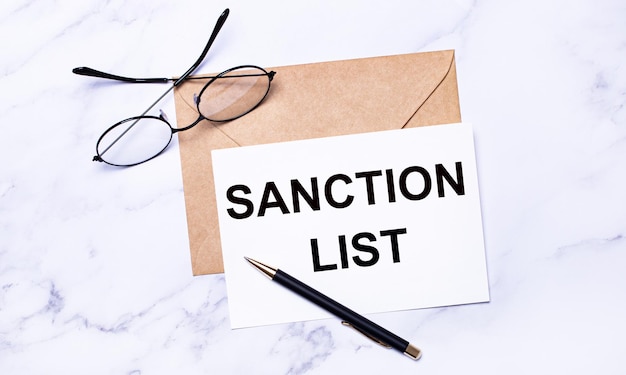 写真 明るい大理石の背景にあるクラフト封筒には、ペンと「sanction list」というテキストが書かれた白いカードが入っています。