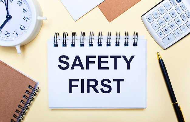 사진 밝은 표면, 흰색 알람 시계, 계산기, 펜 및 safety first 텍스트가있는 노트북