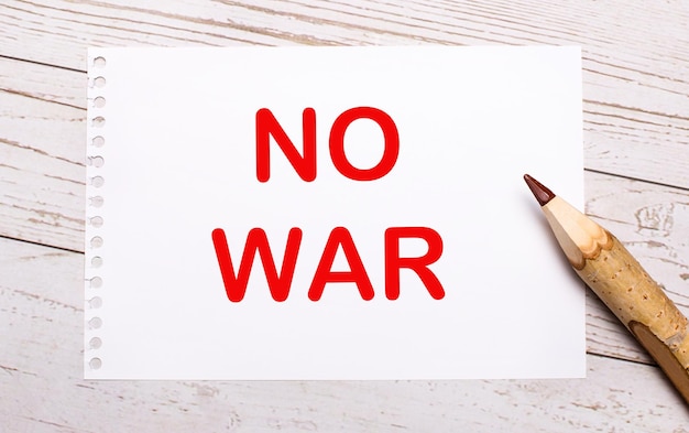 写真 明るい木製の背景に、色鉛筆と、no war というテキストが書かれた白い紙