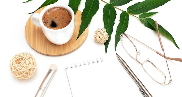 흰색 테이블에는 펜, 안경, 식물, 노트북 및 커피 한 잔이 있습니다. 여자 사무실 책상입니다. 비즈니스 개념입니다. 플랫 레이