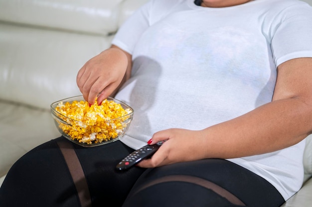 Onbekende dikke vrouw geniet van popcorn.