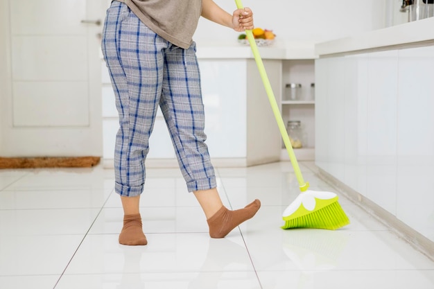 Onbekende vrouw die vloeren schoonmaakt met een bezem