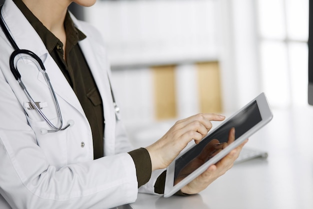Onbekende vrouwelijke arts die tabletcomputer in kliniek gebruikt. Perfecte medische service in het ziekenhuis. Geneeskunde concept.