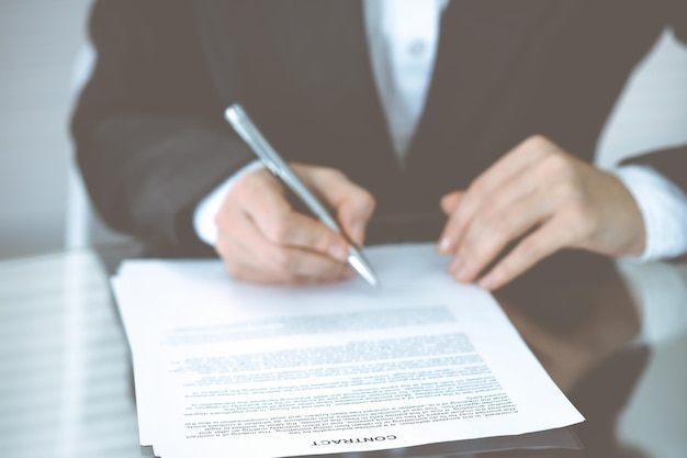Onbekende vrouwelijke handen met pen over document van contract. Overeenkomst ondertekenen of bedrijfsconcept.
