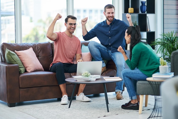 Once youve tasted success mediocre will never be an option Shot of a group of young businesspeople cheering while using a laptop together in a modern office