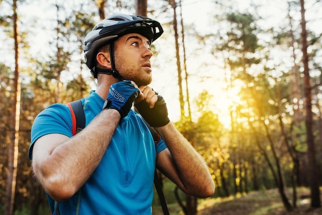 Onderaanzicht close-up portret van serieuze en attente rijder sluit de beschermende helm buitenshuis en kijkt weg, nadenkend over route reisconcept sport levensstijl