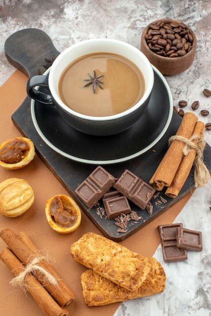 Onderaanzicht kopje koffie chocolade kaneelstokjes koekjes op houten bord gebrande koffiebonen in houten kom op tafel